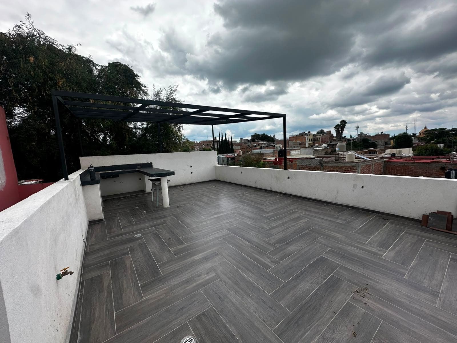 La terraza: pérgola de herrería negra, pretiles blancos y piso de porcelanato en espiga